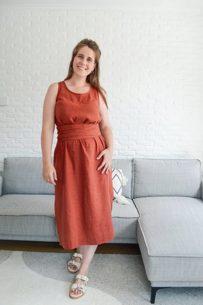 Woman wearing the Rennie Dress sewing pattern from In the Folds on The Fold Line. A dress pattern made in linen, linen blends, cotton, gauze, chambray, sateen, silk (crepe de chine or habotai) or viscose (rayon) fabrics, featuring a boxy relaxed-fit, calf-length, sleeveless, bust darts, scoop neckline, side hem splits, and optional shaped belt.