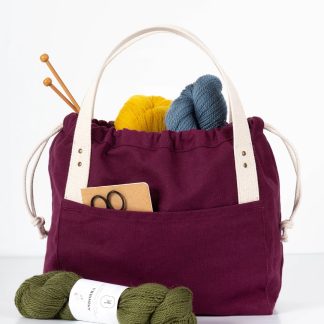 Photo showing the Town Bag sewing pattern from Grainline Studio on The Fold Line. A bag pattern made in canvas fabrics, featuring a drawstring closure, interior pockets, tote-style handles, external front and back pockets.