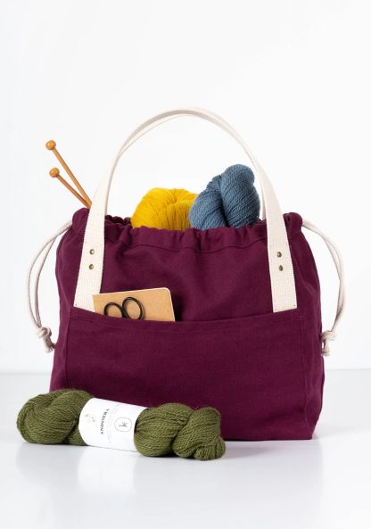 Photo showing the Town Bag sewing pattern from Grainline Studio on The Fold Line. A bag pattern made in canvas fabrics, featuring a drawstring closure, interior pockets, tote-style handles, external front and back pockets.
