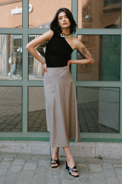 Woman wearing the Willow Skirt sewing pattern from JULIANA MARTEJEVS on The Fold Line. A skirt pattern made in wool or cotton fabrics, featuring an asymmetric silhouette, midi length, waist darts, and invisible zip closure.