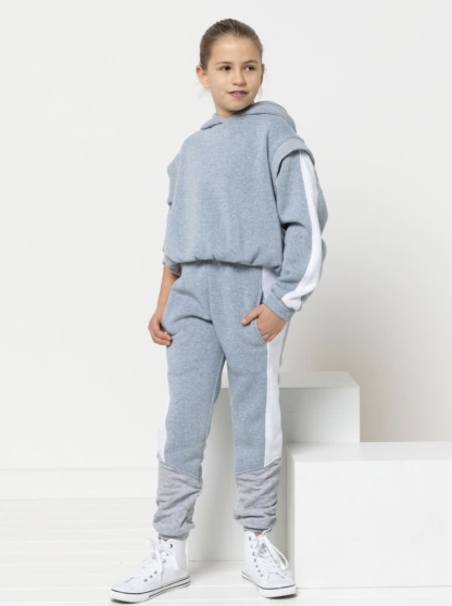 Child wearing the Child/Teen Beckett Sweater sewing pattern from Style Arc on The Fold Line. A hoodie pattern made in fleece, jersey, or sweater knit fabrics, featuring a pull-on style, hood, elasticated waistband and sleeve cuffs, armhole inserts, and sleeve panels.