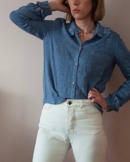 Woman wearing the Belinda Button-up Shirt sewing pattern from French Navy on The Fold Line. A T-shirt pattern made in viscose, shirting cotton, chambray, linen, linen/viscose blends, or cotton poplin fabrics, featuring long-sleeves, dartless bodice, relaxed boxy silhouette, rounded ruffled collar, ruffled sleeve cuffs, chest patch pocket and front button closure.