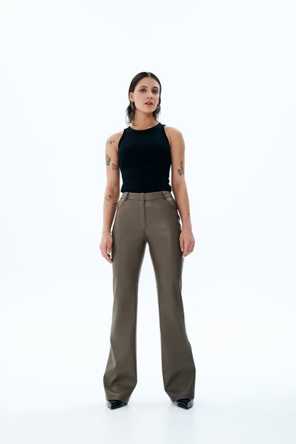 Woman wearing the Candice Trousers sewing pattern from Vikisews on The Fold Line. A trouser pattern made in faux leather, faux suede or leather fabrics, featuring a close-fit, flared leg, below ankle length, front slash pockets, back yoke, back patch pockets, waistband with belt loops and snap closure, fly front zipper, and decorative topstitching.