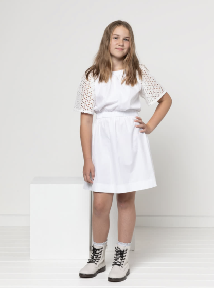 Child wearing the Child/Teen Delta Top and Dress sewing pattern from Style Arc on The Fold Line. A dress pattern made in cotton, linen, cotton/linen blend or rayon fabrics, featuring a gathered elasticated neckline and waist, and short raglan sleeves.