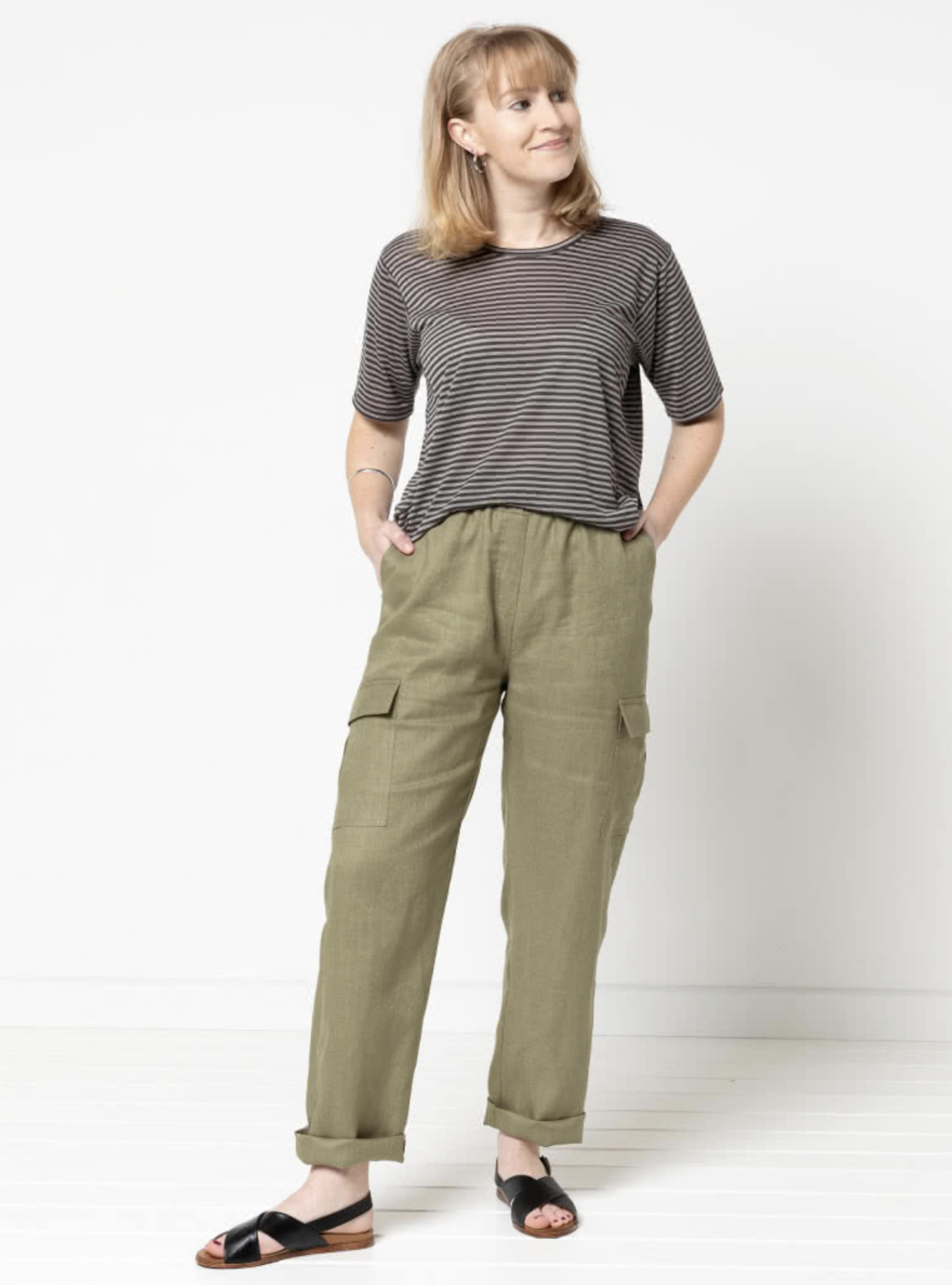 Woman wearing the Delta Cargo Pant sewing pattern from Style Arc on The Fold Line. A cargo trouser pattern made in drill, denim, light wool or washed linen fabrics, featuring a straight leg, elastic waist, faux fly, front slant pockets, back patch pockets, and side leg patch pockets with flap.