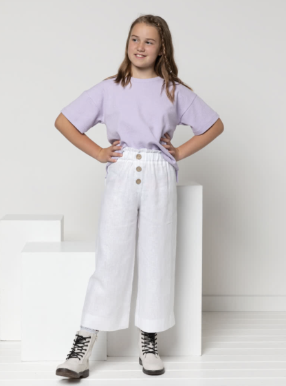 Child wearing the Child/Teen Hayden Tee sewing pattern from Style Arc on The Fold Line. A T-shirt pattern made in T-shirt fabric, jersey or light rugby fabrics, featuring a boxy silhouette, crew neck, dropped shoulder, short sleeves, and high-low hem with side splits.