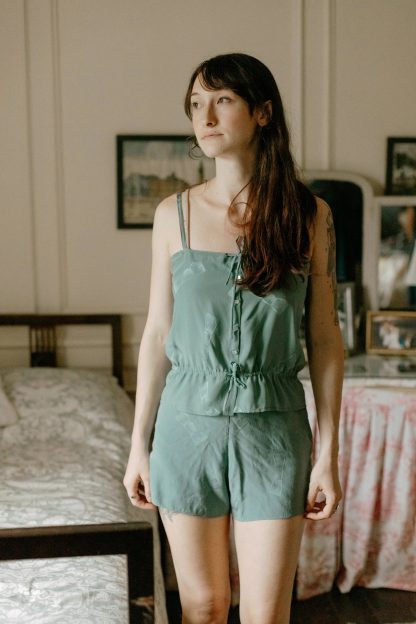 Woman wearing the 219 Intimacies sewing pattern from Folkwear on The Fold Line. A camisole and briefs pattern made in silk, cotton, rayon, synthetics, crepe, challis, voile or satin fabrics, featuring a straight camisole with front button fastening, gathered above the bust and below the waist by ribbon. Tap Pants have side snap closure and low waist.