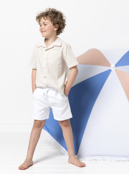 Child wearing the Children’s Oscar Short sewing pattern from Style Arc on The Fold Line. A shorts pattern made in drill, denim, cotton or linen fabrics, featuring an elasticated waist with cord drawstring, faux fly front, crotch insert, front slant pockets and back patch pocket.