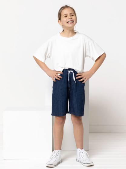 Child wearing the Child/Teen Oscar Short sewing pattern from Style Arc on The Fold Line. A shorts pattern made in drill, denim, cotton or linen fabrics, featuring an elastic waist, faux fly front, crotch insert, front slant pockets and back patch pocket.