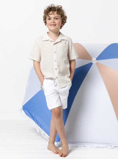 Child wearing the Children’s Rhys Overshirt sewing pattern from Style Arc on The Fold Line. A shirt pattern made in cotton, linen or cotton/linen blend fabrics, featuring a short sleeve, collar, double yoke, button front, chest pocket and shaped hemline.
