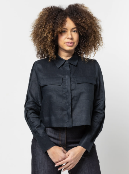 Woman wearing the Smith Woven Jacket sewing pattern from Style Arc on The Fold Line. A jacket pattern made in linen, cotton, silk, crepe, or rayon fabrics, featuring a cropped length, button-front closure, two-piece collar, front and back yokes, back pleat, front patch pockets with flaps, and wide hem facing.