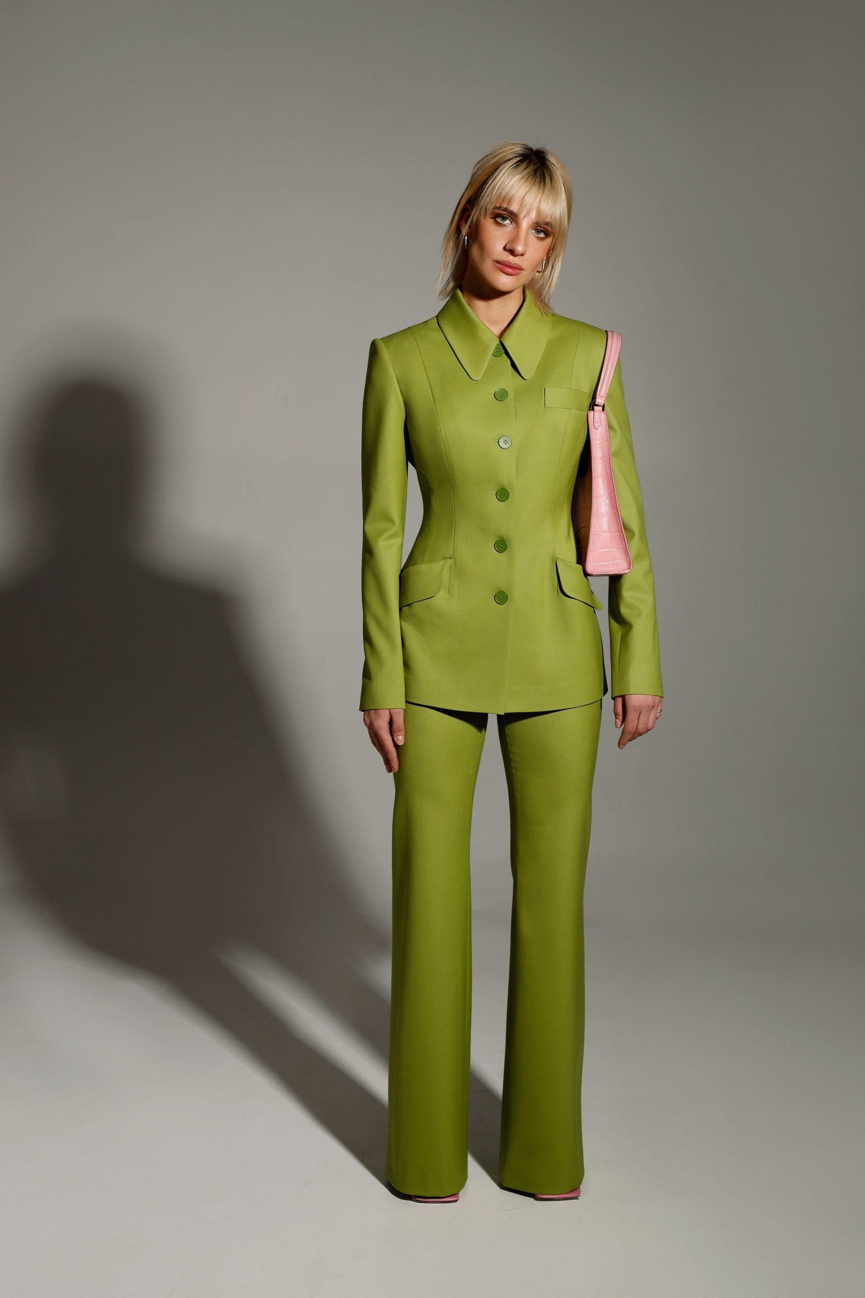 Woman wearing the Solange Blazer sewing pattern from Vikisews on The Fold Line. A blazer pattern made in suiting wool, or gabardine fabrics, featuring a semi fit, single-breasted, accentuated waist, princess seams, front pocket with flap, centre back seam, collar and collar stand, semi-fitted two-piece long sleeves, shoulder pads, fully lined, front button closure and below-hip length.