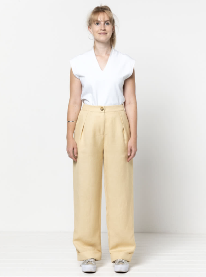 Woman wearing the Spencer Woven Pant sewing pattern from Style Arc on The Fold Line. A trouser pattern made in linen, wool, cotton or gabardine fabrics, featuring a wide leg, cuffed hem, shaped waistband, back waist darts, front knife pleats, fly zip, front angled pockets and back welt pocket.
