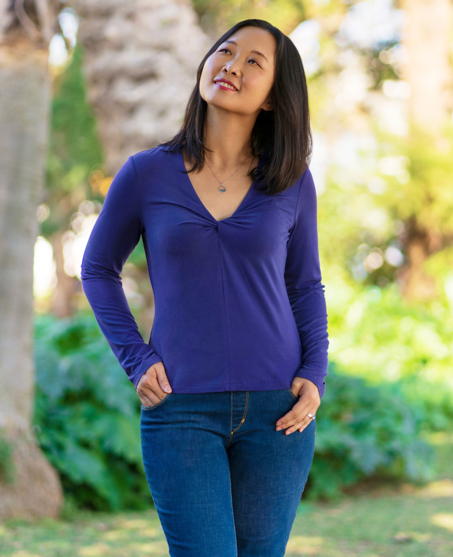 Woman wearing the Zakopane Top sewing pattern from Itch to Stitch on The Fold Line. A top pattern made in lightweight knit fabrics, featuring a V-neckline with twist at centre front, long sleeves, and is fitted.