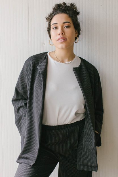 Woman wearing the Basic Jacket sewing pattern from JULIANA MARTEJEVS on The Fold Line. A jacket pattern made in wool fabrics, featuring a round neck, front patch pockets, full length sleeves, top of thigh length, relaxed fit, and optional snap button closure.