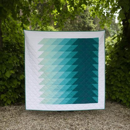 Image showing the Ripple Quilt sewing pattern from Lou Orth Designs on The Fold Line. A quilt pattern made in quilting cotton fabrics, featuring a bold, modern ripple design that looks stunning in any fabric choice.
