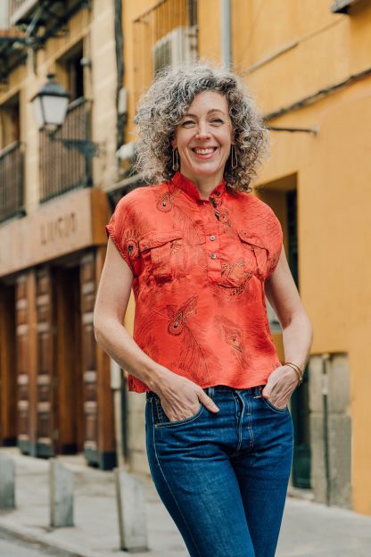 Woman wearing the Santa Rosa Top sewing pattern from Liesl + Co on The Fold Line. A top pattern made in rayon, poly satin, silk satin and crepe fabrics, featuring a band collar, popover button placket, short dolman sleeves, relaxed fit, dropped shoulders, and centre back box pleat.