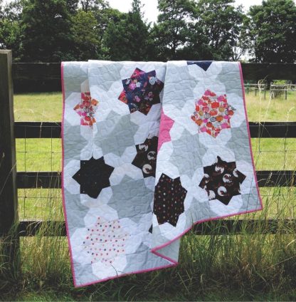 Photo showing the Suncatcher Quilt sewing pattern from Lou Orth Designs on The Fold Line. A quilt pattern made in quilting cotton fabrics, featuring a fun star quilt pattern that looks beautiful in any fabric.