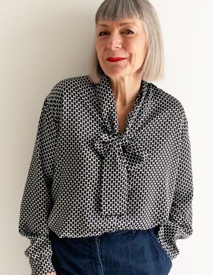 Woman wearing the Tie Front Blouse sewing pattern from The Maker's Atelier on The Fold Line. A blouse pattern made in silk, Tencel, viscose, fine cotton or Tana lawn fabrics, featuring cuffed sleeves with button closure, relaxed fit, pussy bow neck tie, front button closure and slightly dropped shoulders.