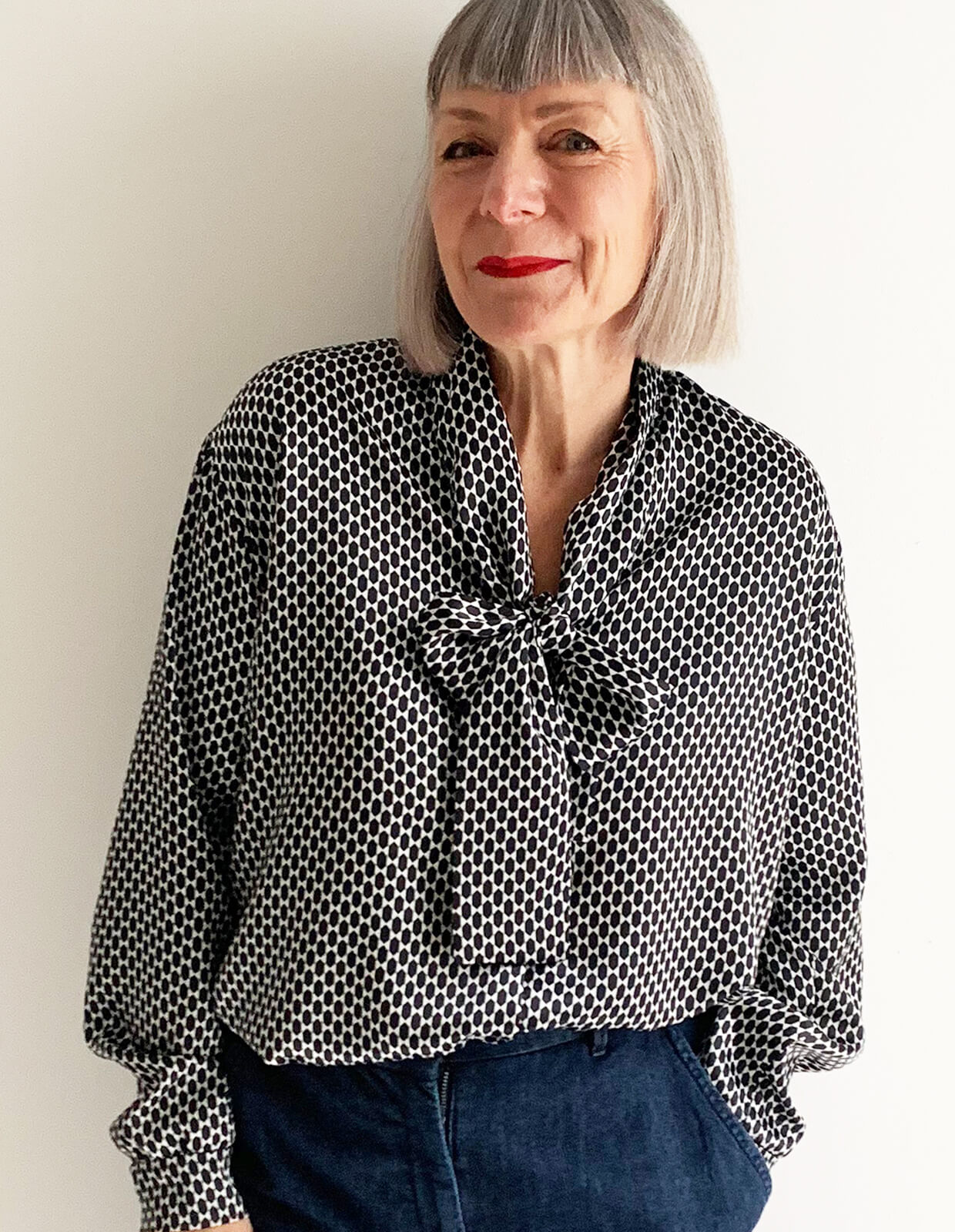 Woman wearing the Tie Front Blouse sewing pattern from The Maker's Atelier on The Fold Line. A blouse pattern made in silk, Tencel, viscose, fine cotton or Tana lawn fabrics, featuring cuffed sleeves with button closure, relaxed fit, pussy bow neck tie, front button closure and slightly dropped shoulders.