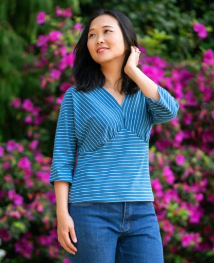 Woman wearing the Amador Top sewing pattern from Itch to Stitch on The Fold Line. A top pattern made in athletic knit, ITY, double-brushed poly and cotton Lycra fabrics, featuring a V-neck, empire line with under bust gathers, and elbow-length dolman sleeves.