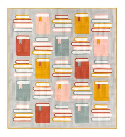 Photo showing the Book Nook Quilt sewing pattern from Pen and Paper Patterns on The Fold Line. A quilt pattern made in quilting cotton fabrics, featuring an alternating upright book with a four stack of books in blues, reds, yellows and pinks on a grey background.