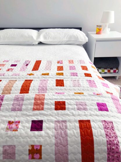 Photo showing the Dot and Dash Quilt sewing pattern from Modern Handcraft on The Fold Line. A quilt pattern made in quilting cotton fabrics, featuring a dot and dash design, using square and rectangular shapes on a white background.