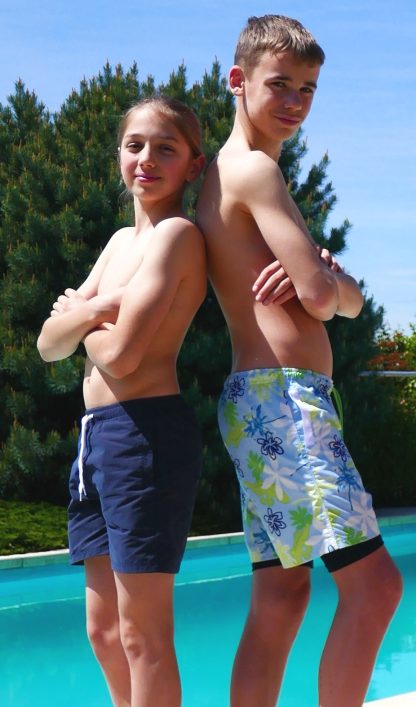Boys wearing the Child/Teen Gecko Swim/Sports Shorts sewing pattern from Petits D'om on The Fold Line. A swim or sports shorts pattern made in medium woven fabrics or polyamide and polyester fabrics featuring a mid-thigh length, elastic waistband with drawstring, front pockets with welt-like bands and optional lining that extends below the hem.