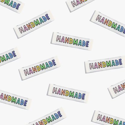 Photo showing 'Handmade Rainbow' Cotton Labels from Kylie & The Machine on The Fold Line. A washable, durable, and non-scratchy cotton label featuring an ivory background and rainbow coloured text, they are all ready to be sewn into your handmade clothes.