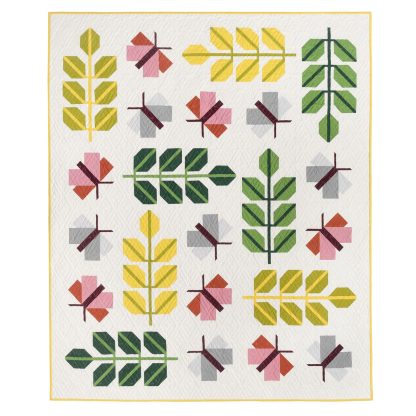 Photo showing the Oak Moth Quilt sewing pattern from Pen and Paper Patterns on The Fold Line. A quilt pattern made in quilting cotton fabrics, featuring multicoloured moths and fern leaves on a pale cream background with instructions for piecing a single moth and fern block.
