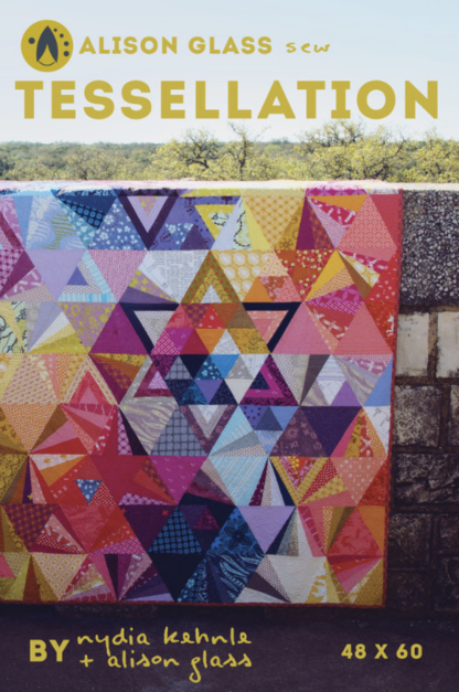 Photo showing the Tessellation Quilt sewing pattern from Alison Glass on The Fold Line. A quilt pattern made in quilting cotton fabrics, featuring a design using triangles of all sizes and shapes in a rainbow of colours.