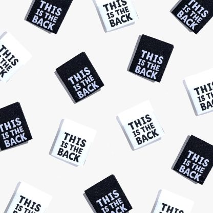 Photo showing 'This Is the Back' Cotton Labels from Kylie & The Machine on The Fold Line. A washable, durable, and non-scratchy cotton label featuring a white or black background with white or black coloured text, they are all ready to be sewn into your handmade clothes.