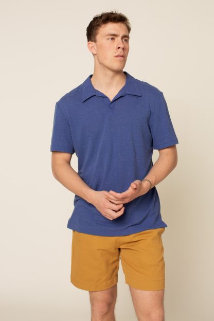 Man wearing the Men's Draper Polo Shirt sewing pattern from Wardrobe by Me on The Fold Line. A Polo Shirt pattern made in jersey, activewear knit, or fancy knit fabrics, featuring a relaxed fit, polo collar, button placket, side vents, and short sleeves.