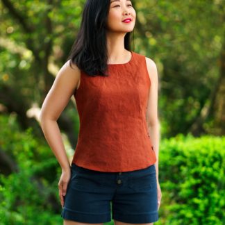 Woman wearing the Santorini Tank sewing pattern from Itch to Stitch on The Fold Line. A tank pattern made in linen, chambray, broadcloth and plain weave cotton fabrics, featuring a semi-fit, princess seams, high hip length, neckline and armholes facings, and side seam button closure.