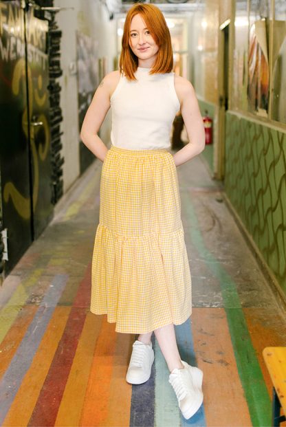 Woman wearing the Abbie Skirt sewing pattern from JULIANA MARTEJEVS on The Fold Line. A skirt pattern made in cotton poplin fabrics, featuring a relaxed fit, midi length, elasticated waist, side pockets and deep tier.