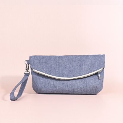 Photo showing the Arch Clutch sewing pattern from Kylie & The Machine on The Fold Line. A clutch bag pattern made in cottons, canvas, denim, or corduroy fabrics, featuring a main compartment, internal zipper pocket, wrist strap, and curved zip closure.