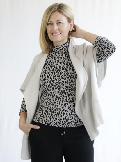 Woman wearing the Debra Zebra Knit Top sewing pattern from Style Arc on The Fold Line. A top pattern made in knit jersey or baby wool fabrics, featuring a high funnel neck, slightly fitted body, and long sleeves.