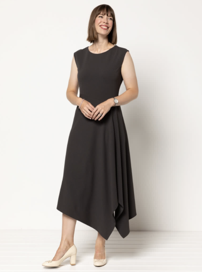 Woman wearing the Elley Designer Knit Dress sewing pattern from Style Arc on The Fold Line. A dress pattern made in ponte or dress weight knit fabrics, featuring a sleeveless, round neck, midi length, slip-on style, angled bodice and asymmetrical hemline.