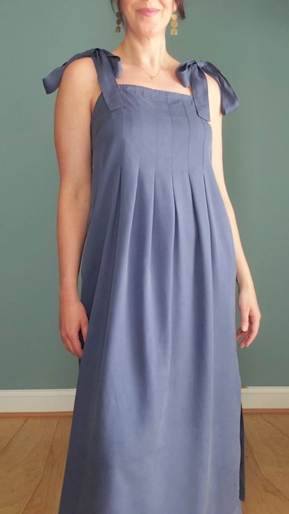Woman wearing the Flora Dress sewing pattern from Pattern Scout on The Fold Line. A sun dress pattern made in rayon, viscose challis, and linen fabrics, featuring wide shoulder straps, wide tucks across bodice, flowy skirt, side seam slits, maxi length and in-seam pockets.