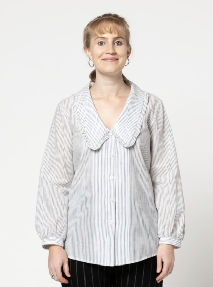 Woman wearing the Kennie Woven Shirt sewing pattern from Style Arc on The Fold Line. A shirt pattern made in cotton, voile or silk fabrics, featuring a button-front closure, bust darts, deep V-neck, large statement collar edged with a frill, and long sleeves with slip-through cuff.