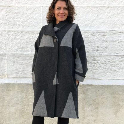 Woman wearing the Soho Coat sewing pattern from Tessuti Fabrics on The Fold Line. A coat pattern made in wool/cashmere blends, wool tweed, wool boucle and double wool crepe and heavy weight linen fabrics, featuring turn back collar, side pockets, dropped shoulders, topstitched side seams, full-length sleeves with rolled back cuffs, unlined and knee length,