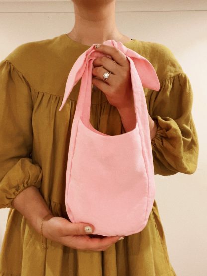 Woman holdling the Frankie Bag sewing pattern from Veronica Tucker on The Fold Line. A reversible tote bag pattern made in linen or compact cotton twill fabrics, featuring a pocket and knotted shoulder ties.