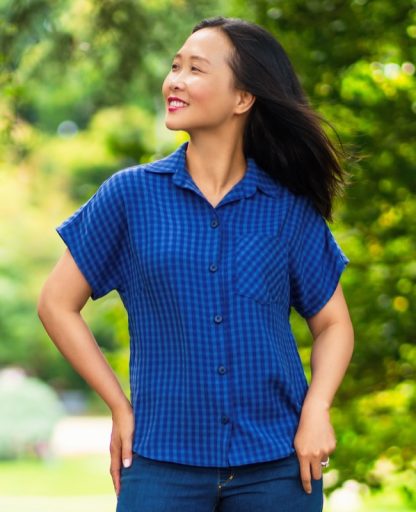 Woman wearing the Nosara Shirt sewing pattern from Itch to Stitch on The Fold Line. A shirt pattern made in shirting, linen, chambray, rayon/viscose challis and plain weave cotton fabrics, featuring a front button closure, collar with stand, back yoke, high-low shirttail hem, and grown-on short sleeves.