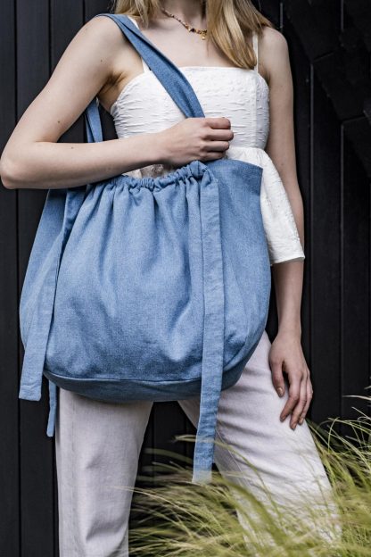 Woman wearing the Mehri Bag sewing pattern from Fibre Mood on The Fold Line. A tote bag pattern made in cottons or linen fabrics, featuring a generous size, full lining, shoulder straps, and adjustable gathered side straps.