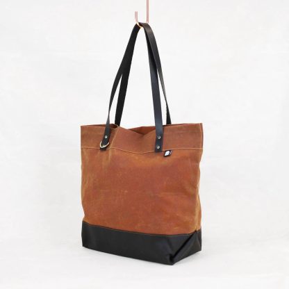 Photo showing the Portsmith Tote Bag sewing pattern from Klum House on The Fold Line. A tote bag pattern made in canvas, waxed canvas, or denim fabrics, featuring leather straps, metal rivets, reinforced base with envelope folds and roomy interior.