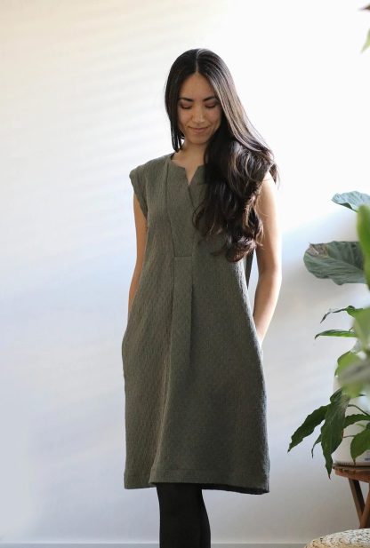 Woman wearing the Sawtell Dress sewing pattern from In the Folds on The Fold Line. A dress pattern made in linen, linen blends, cotton and lightweight denim fabrics, featuring a knee length, inset placket with pleats, bust darts, back yoke, back box pleat, capped sleeves and wide hem, in-set pockets and round neckline with centre front V cut-out.