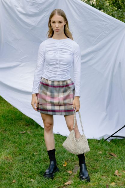 Woman wearing the Mimi Skirt sewing pattern from JULIANA MARTEJEVS on The Fold Line. A skirt pattern made in cotton poplin or wool fabrics, featuring an elastic waistband, in-seam pockets, relaxed fit and mini length.