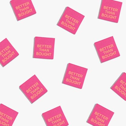 Photo showing 'Better Than Bought' Labels from Kylie & The Machine on The Fold Line. A washable, durable, and non-scratchy label. Included are, 6 woven labels with orange lettering on a pink background. They are all ready to be sewn into your handmade clothes.