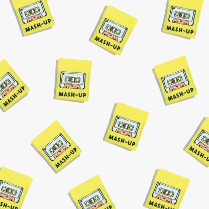 Photo showing 'Mash-Up’ Labels from Kylie & The Machine on The Fold Line. A washable, durable, and non-scratchy label. Included are, 6 woven labels with black lettering on a yellow background. They are all ready to be sewn into your handmade clothes.