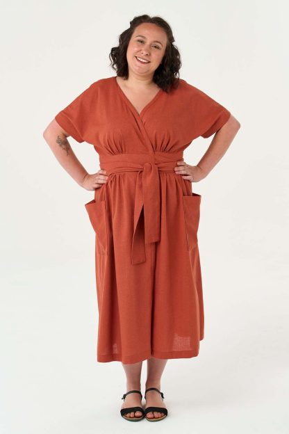 Woman wearing the Norah Dress sewing pattern from Sew Over It on The Fold Line. A wrap dress pattern made in crepe, viscose twills, linen, or linen viscose fabrics, featuring grown-on short sleeves, oversized patch pockets, under bust gathers, back bodice and skirt gathers, midi length, waist tie belt closure, and V-neckline.